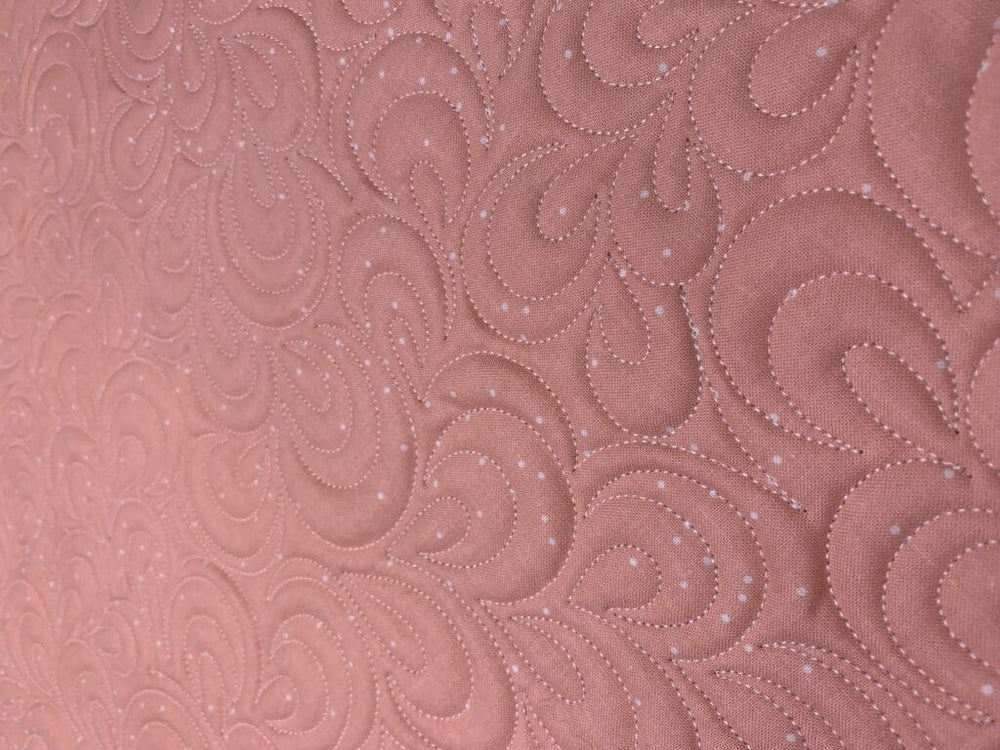 Pink quilted fabric with swirl pattern