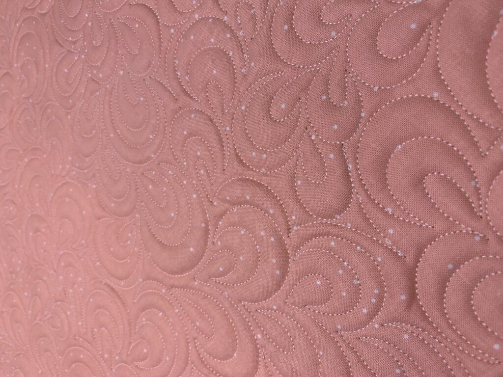 Pink quilted fabric with swirl pattern