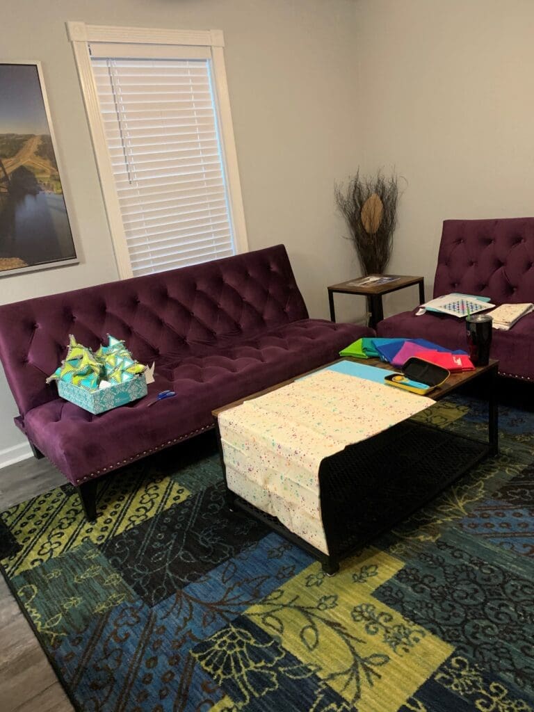 Purple tufted sofas with colorful patterned rug