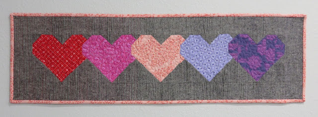 Quilted gray fabric banner with six hearts