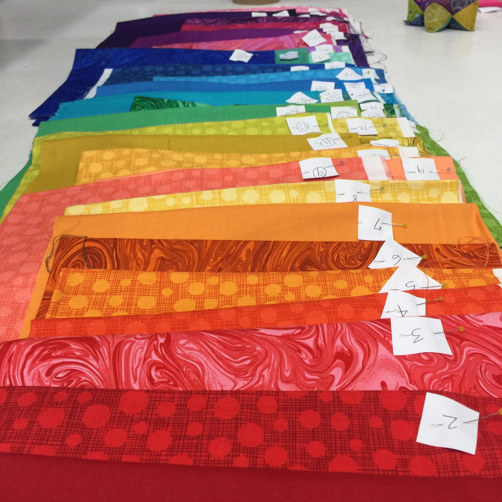 A table with many different colored fabrics on it