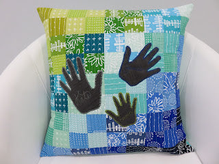 Patchwork pillow with three black handprints