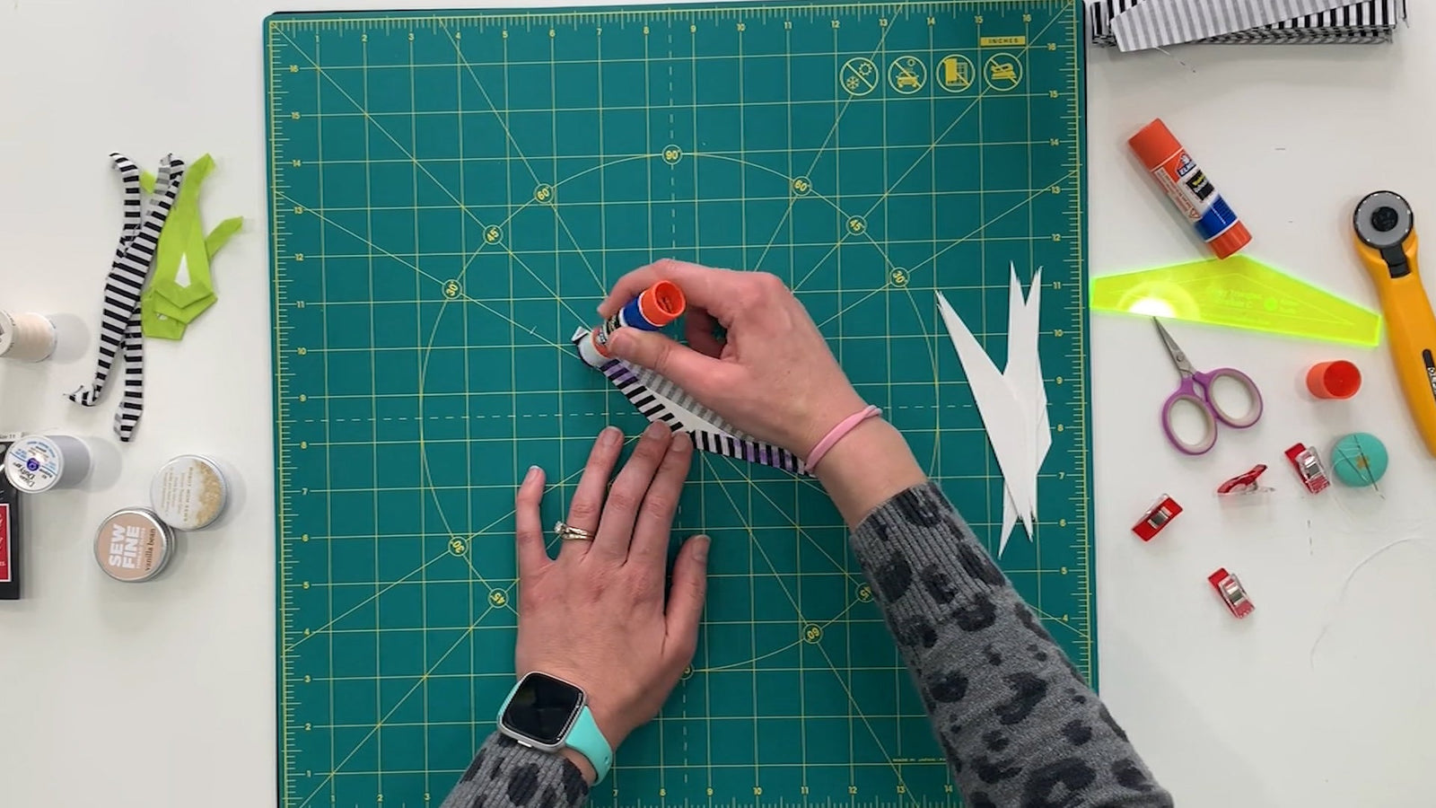 A person using a pair of scissors on a cutting mat.