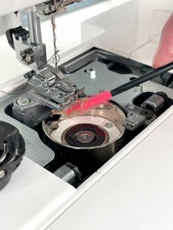 A person is using a metal tool to cut the bottom of a pan.