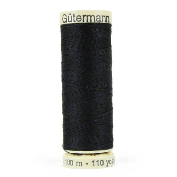 A spool of black thread is sitting on the floor.