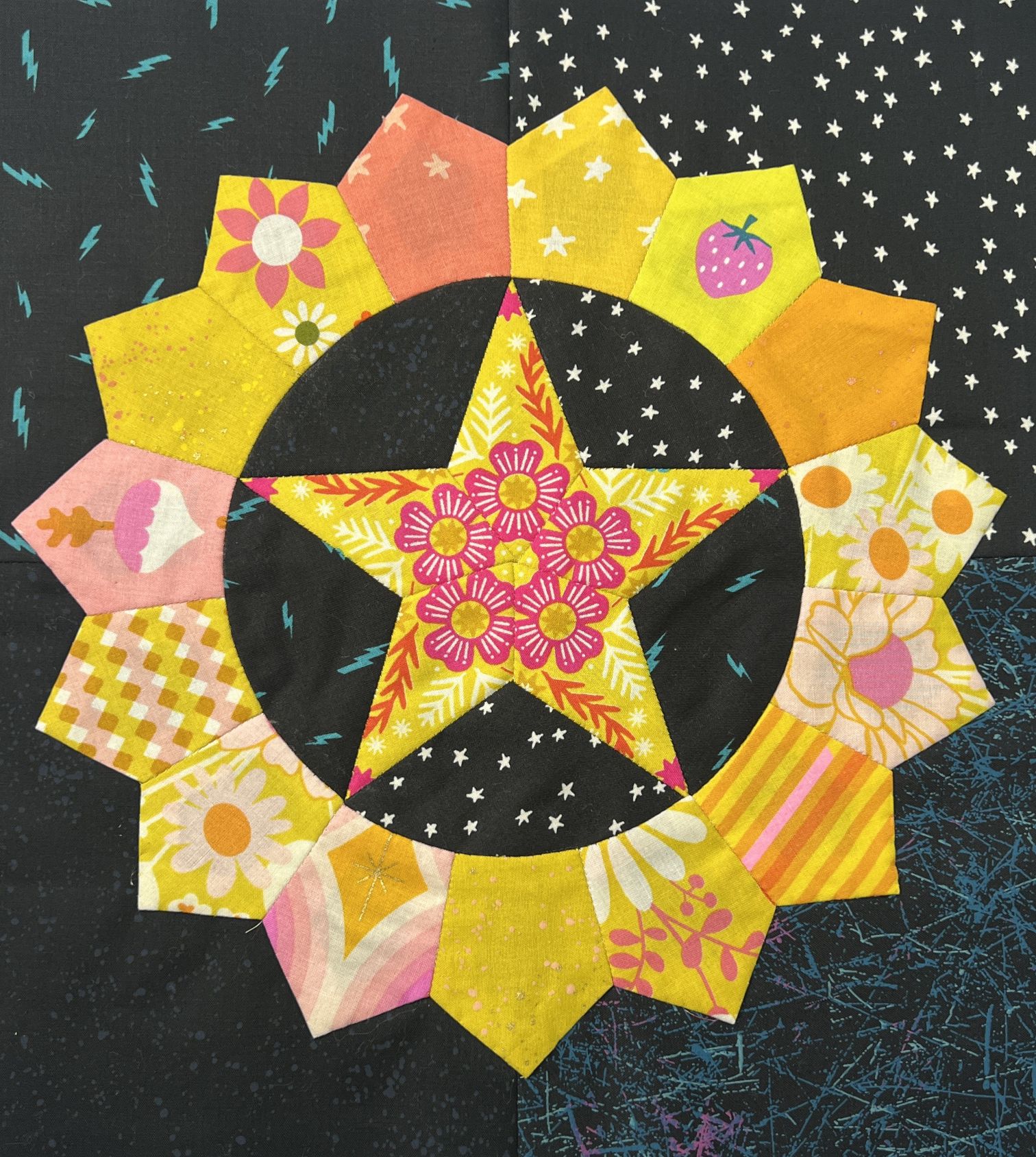 Colorful quilted star and flower pattern on dark fabric.