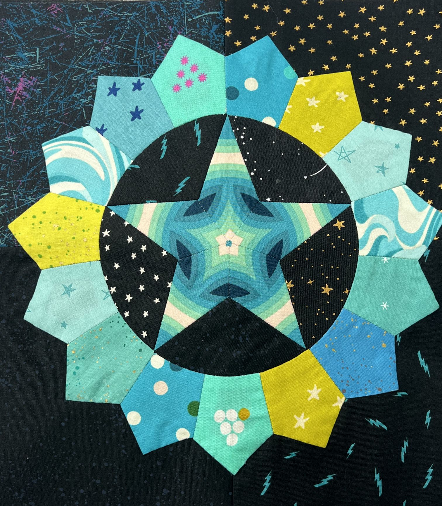 A colorful star-shaped fabric quilt block with various blue and yellow patterns.