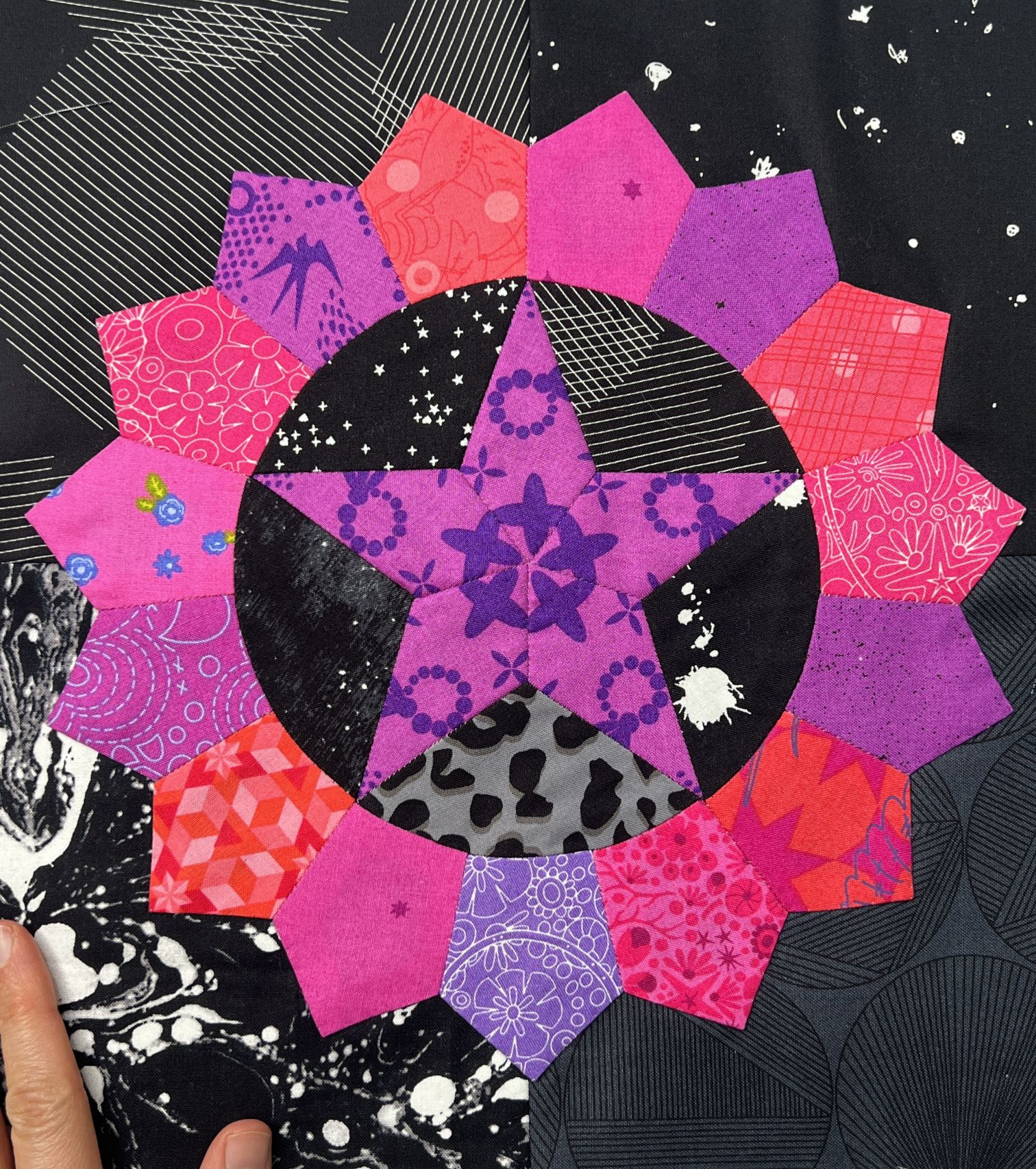 Colorful quilt block with star and geometric patterns in purple, pink, and red.