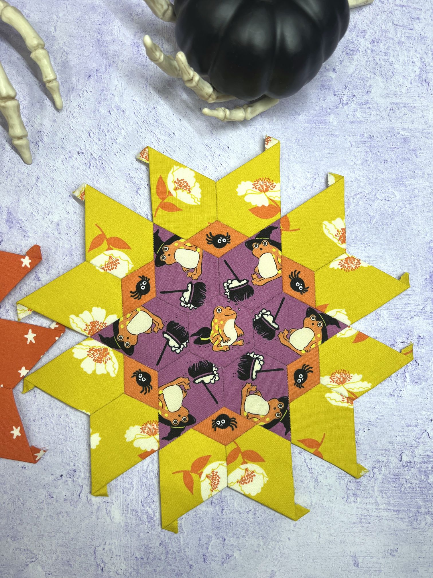 Intricate star-shaped rangoli design with yellow and purple hues.