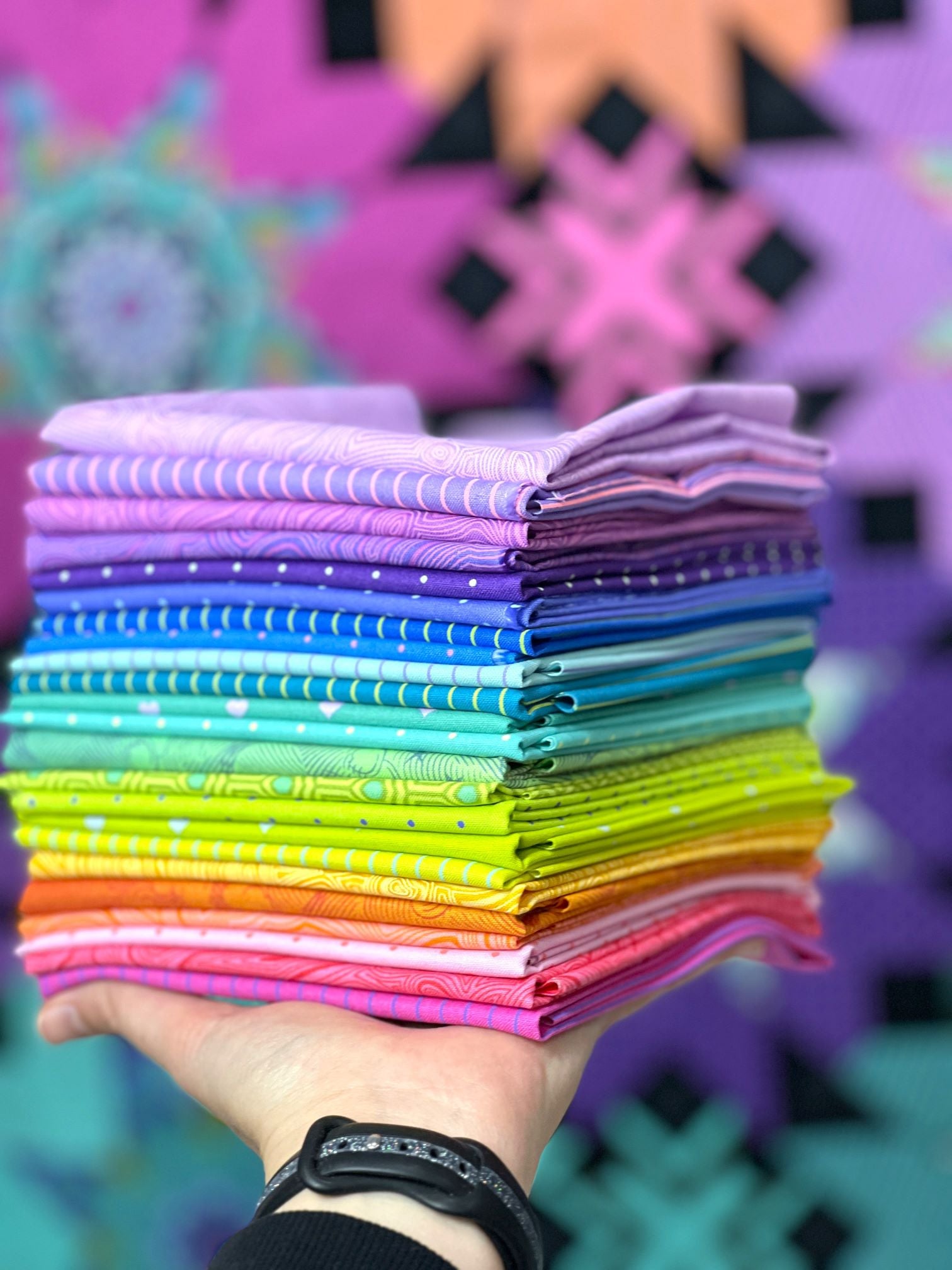 A stack of colorful fabric in front of purple wall.
