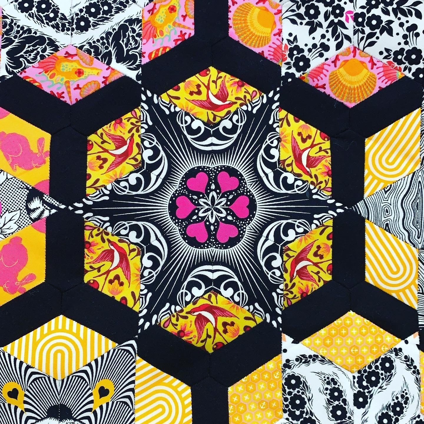 A quilt with different designs of hexagons and flowers.