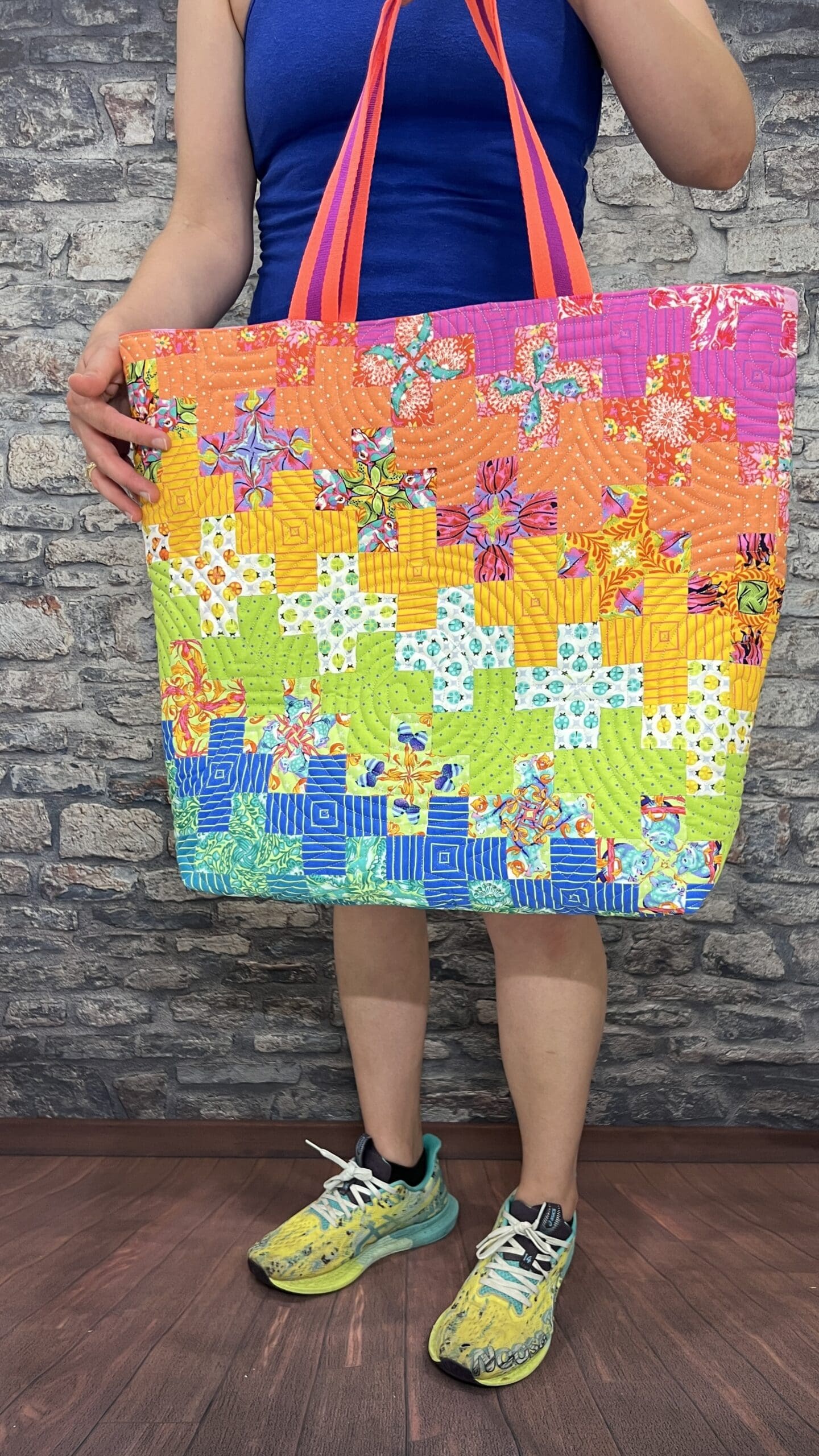 A person holding up a colorful puzzle piece quilt.