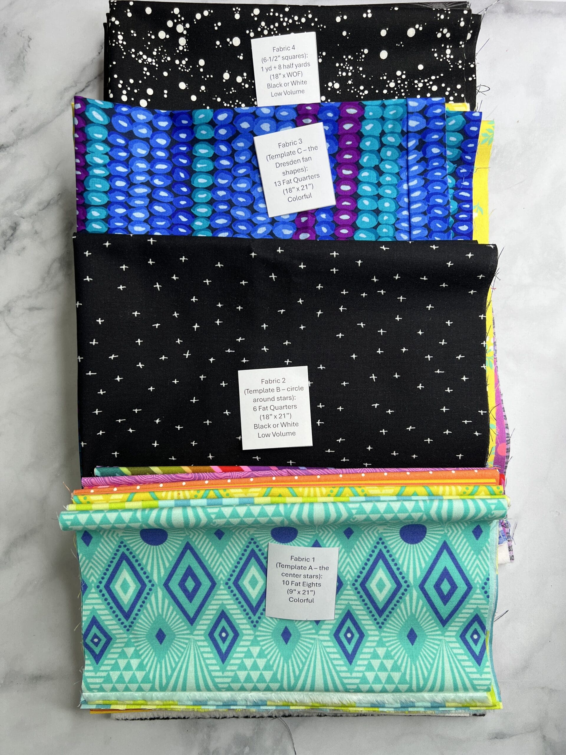Three folded fabric pieces with distinct colorful patterns stacked.