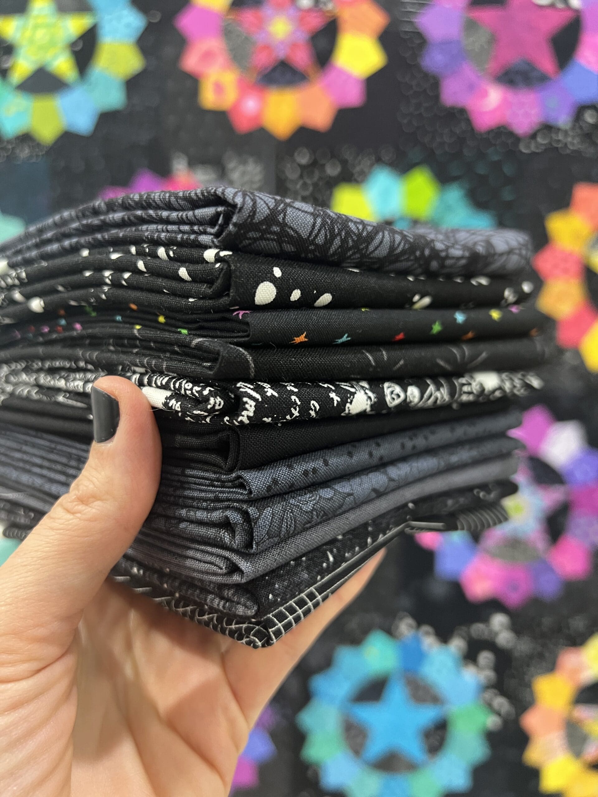 Hand holding a stack of black and white patterned fabric squares.