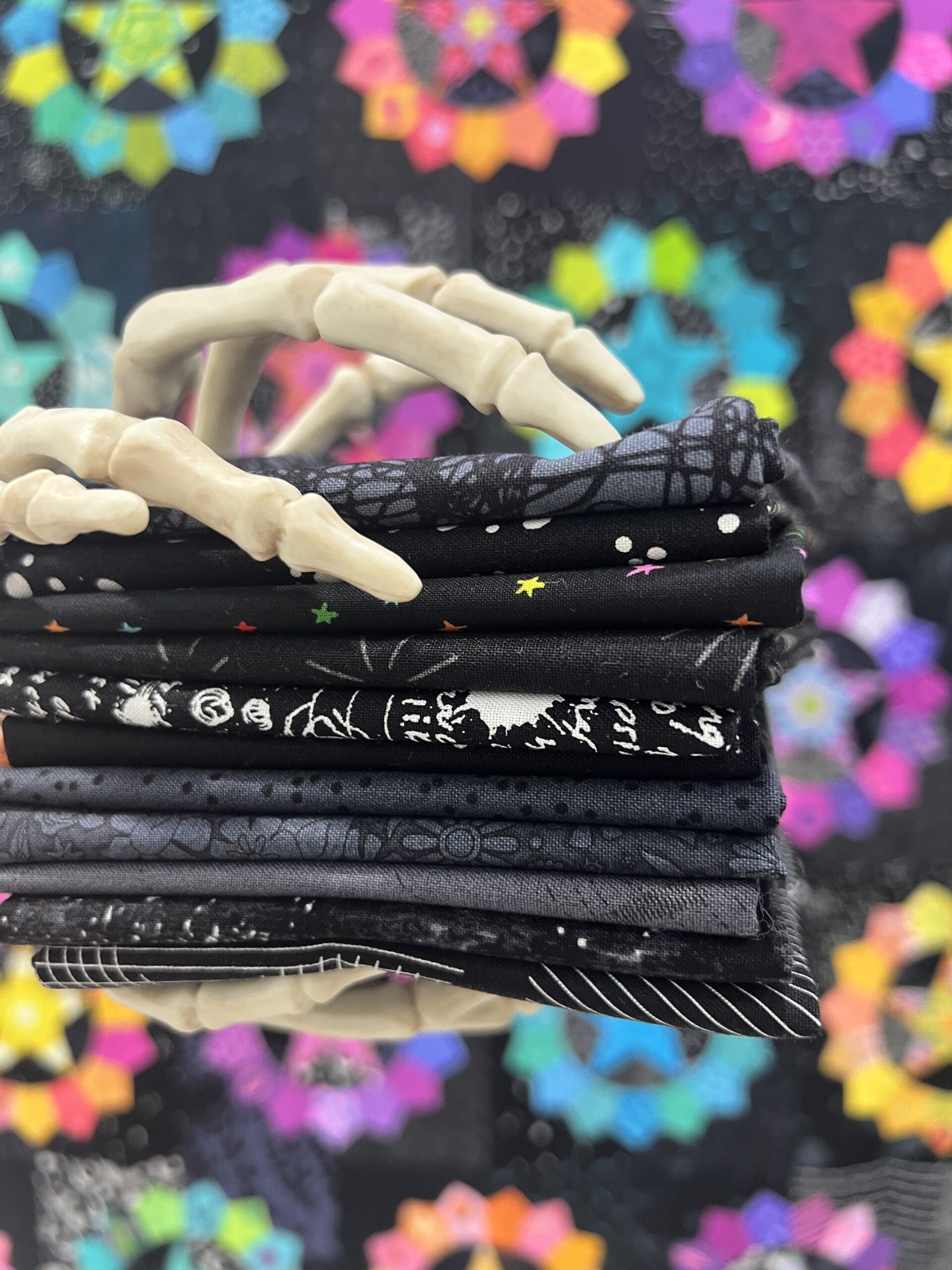 Stack of black fabric pieces with white patterns and a pair of scissors on top.