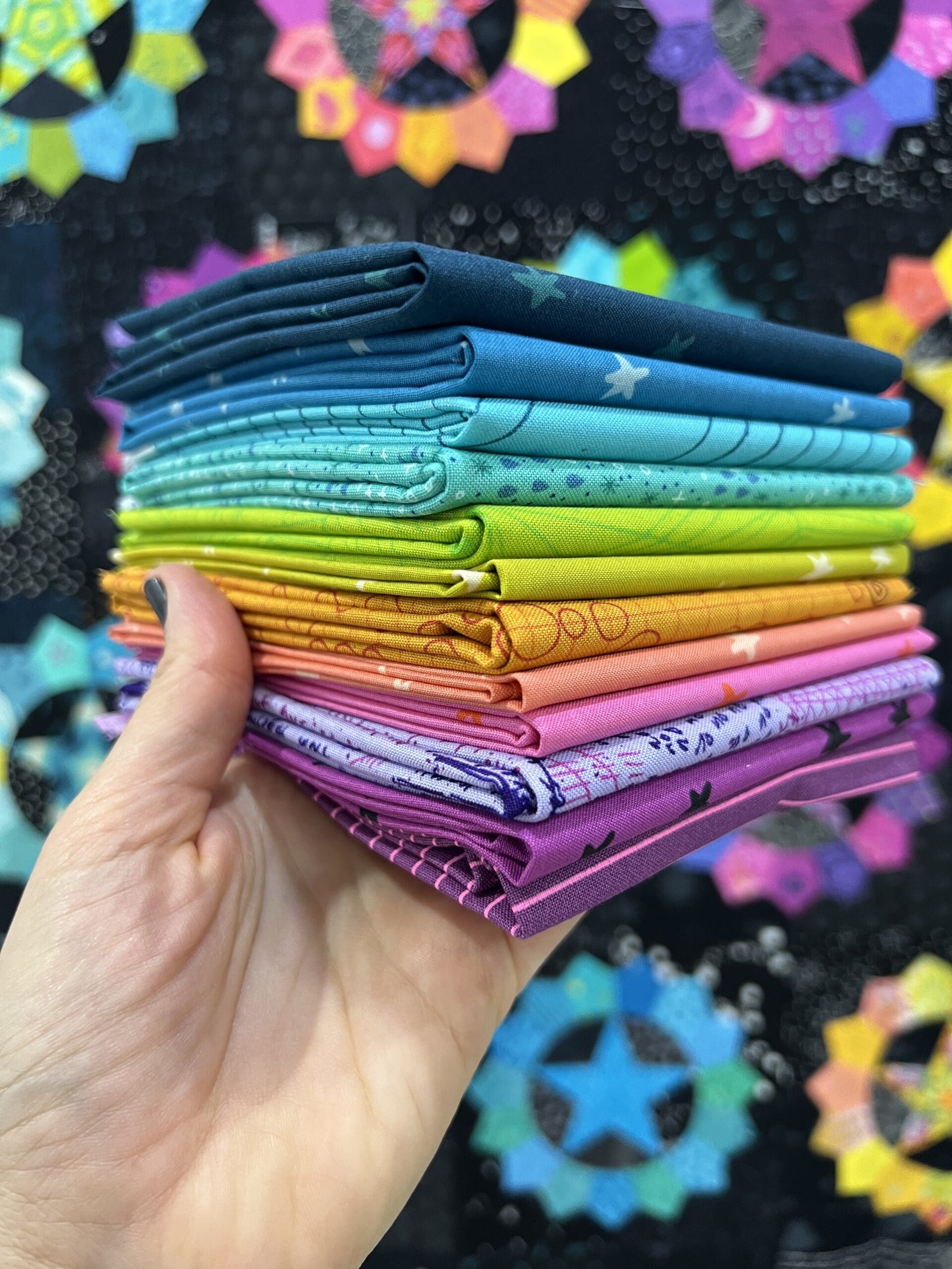 Hand holding a stack of colorful fabric squares.
