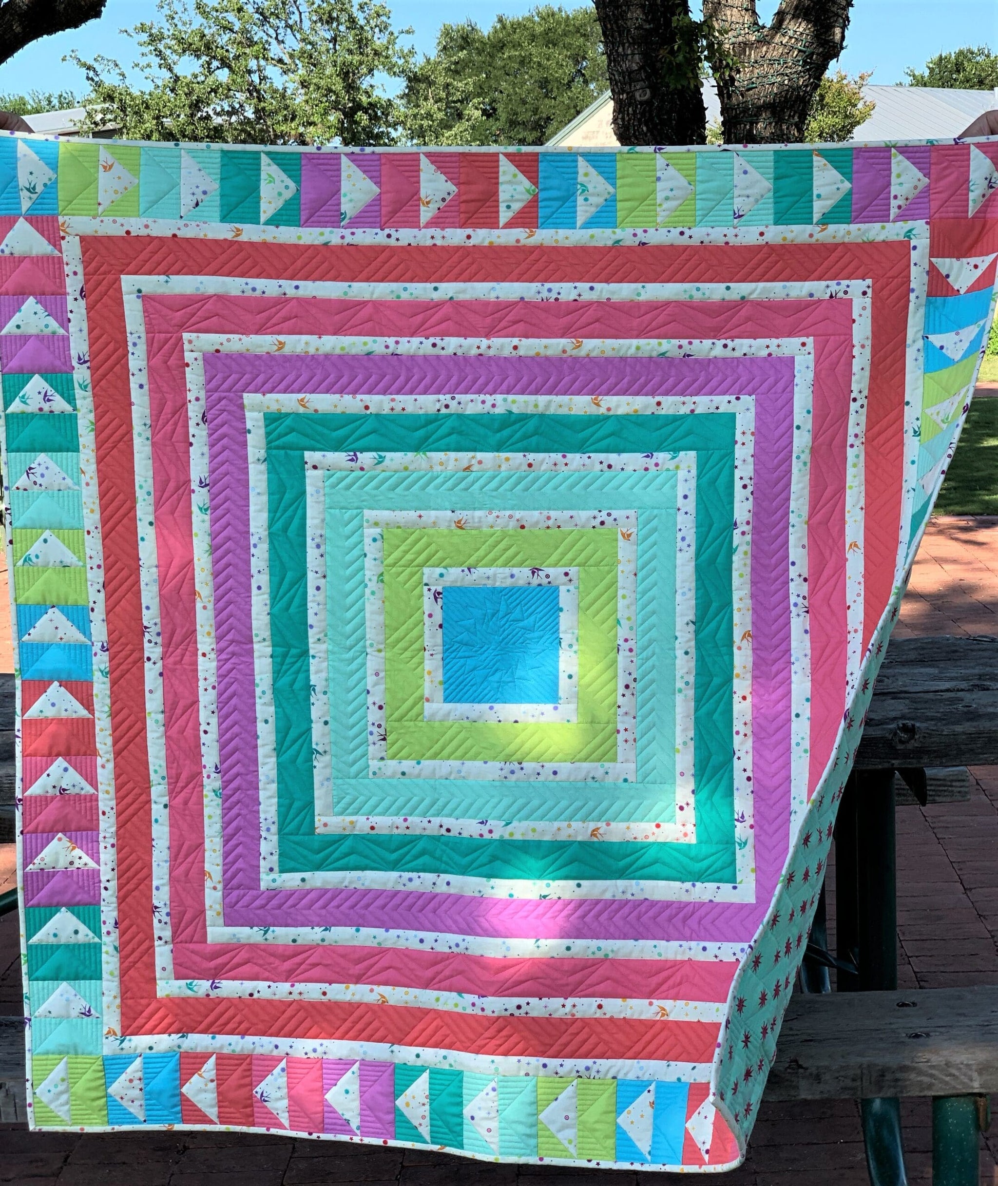 A colorful quilt is sitting on the ground.