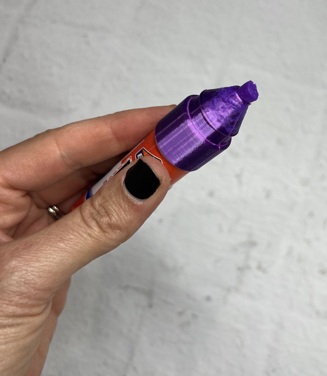 Hand holding a small purple container with a pointed tip.