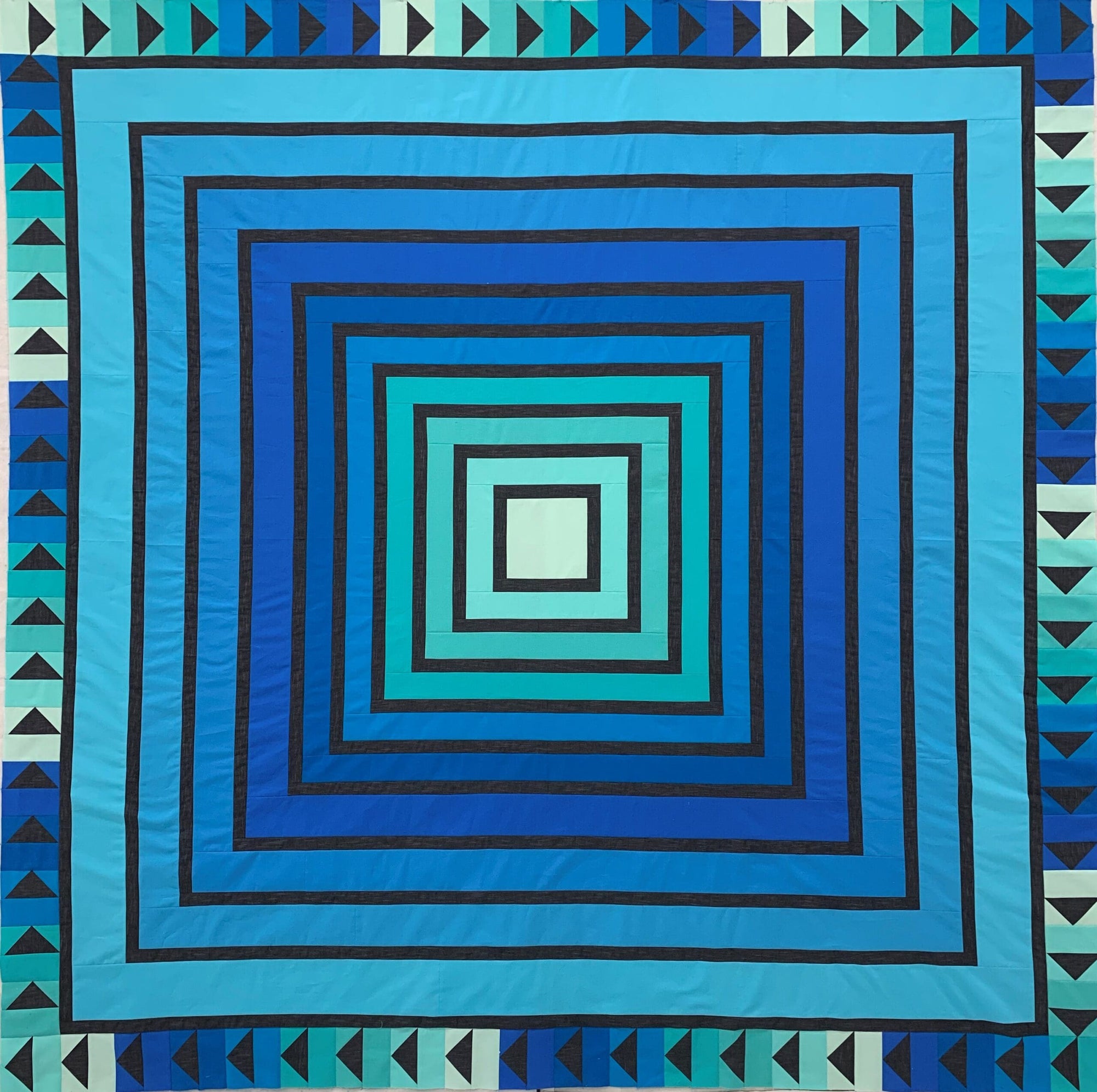 A blue quilt with an abstract design.