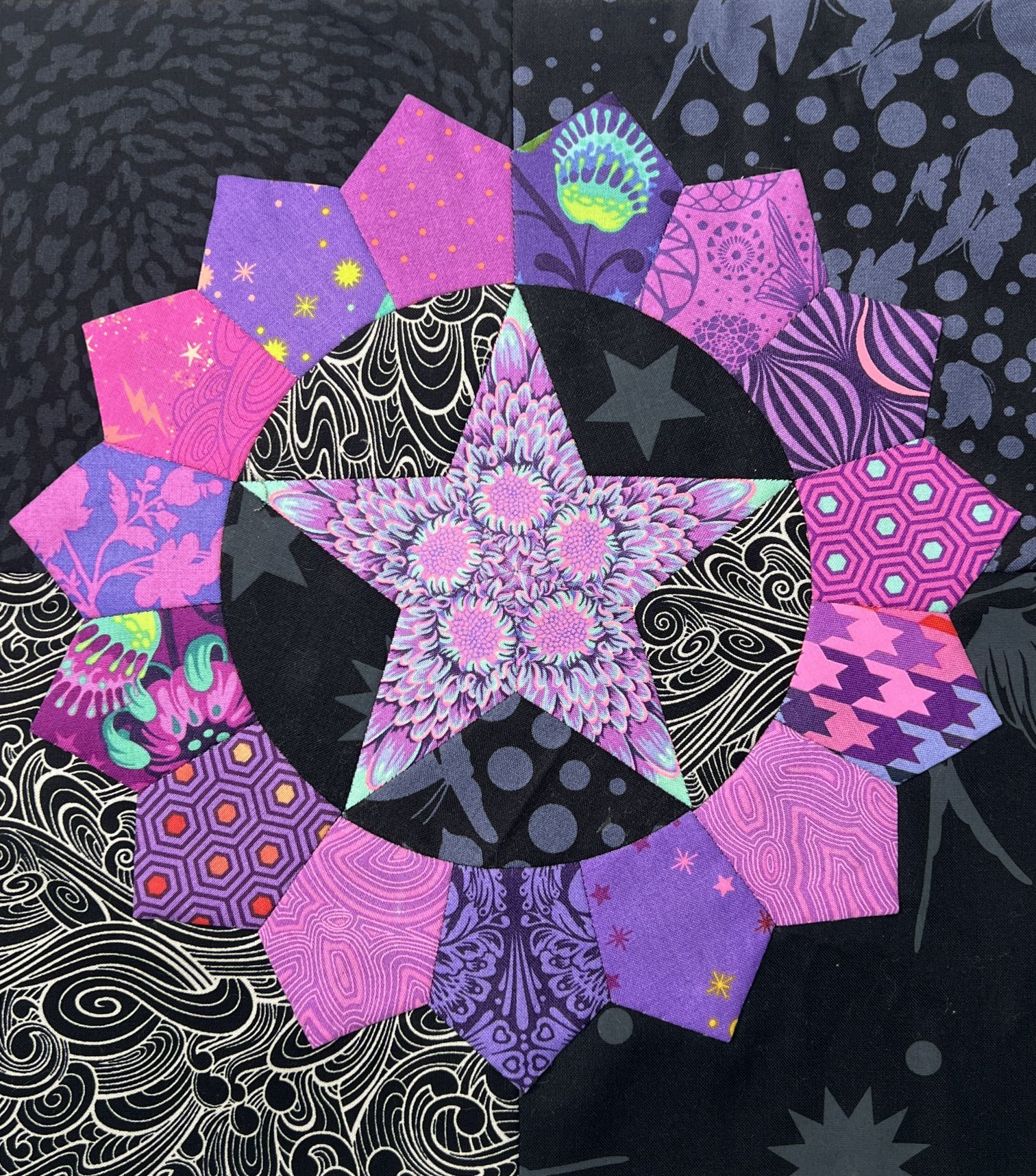 A vibrant quilt with purple, pink, and black geometric patterns.