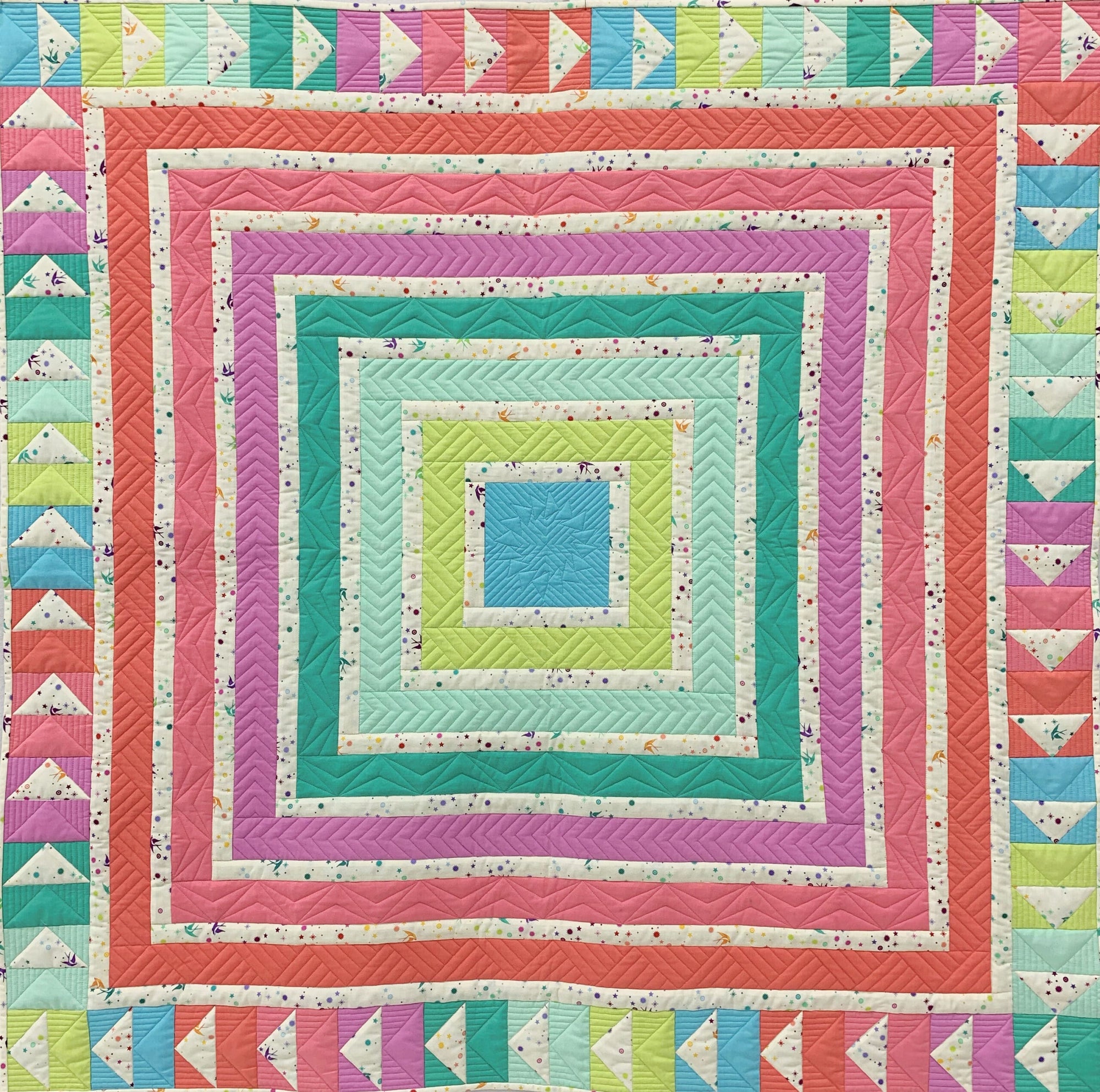 A colorful quilt with squares and triangles in the center.