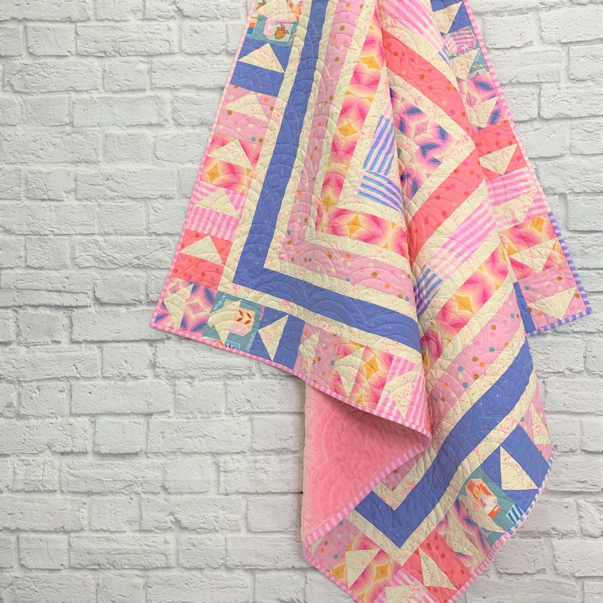 A quilt hanging on the wall of a brick room.