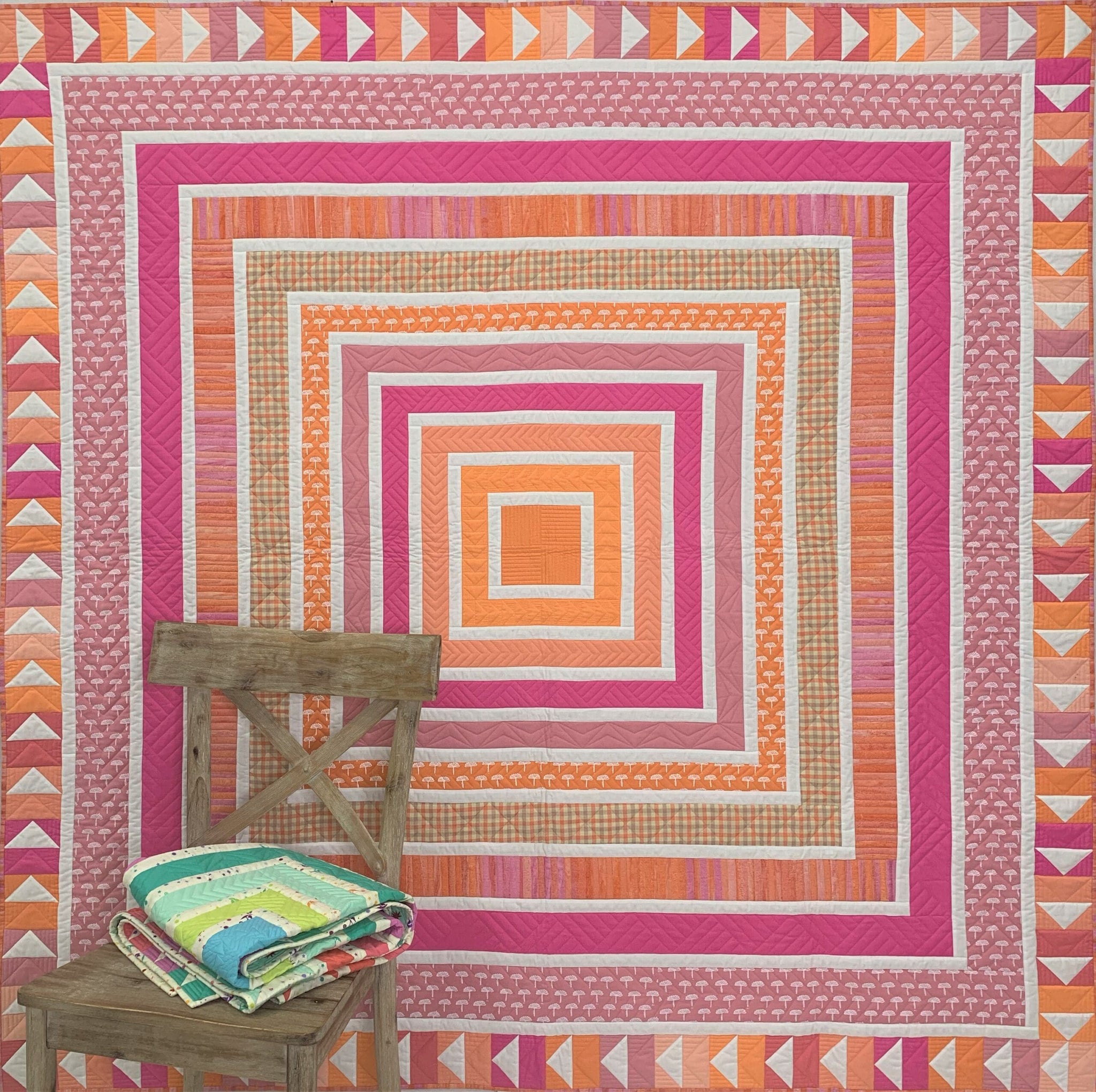 A quilt with an orange and pink design on it.