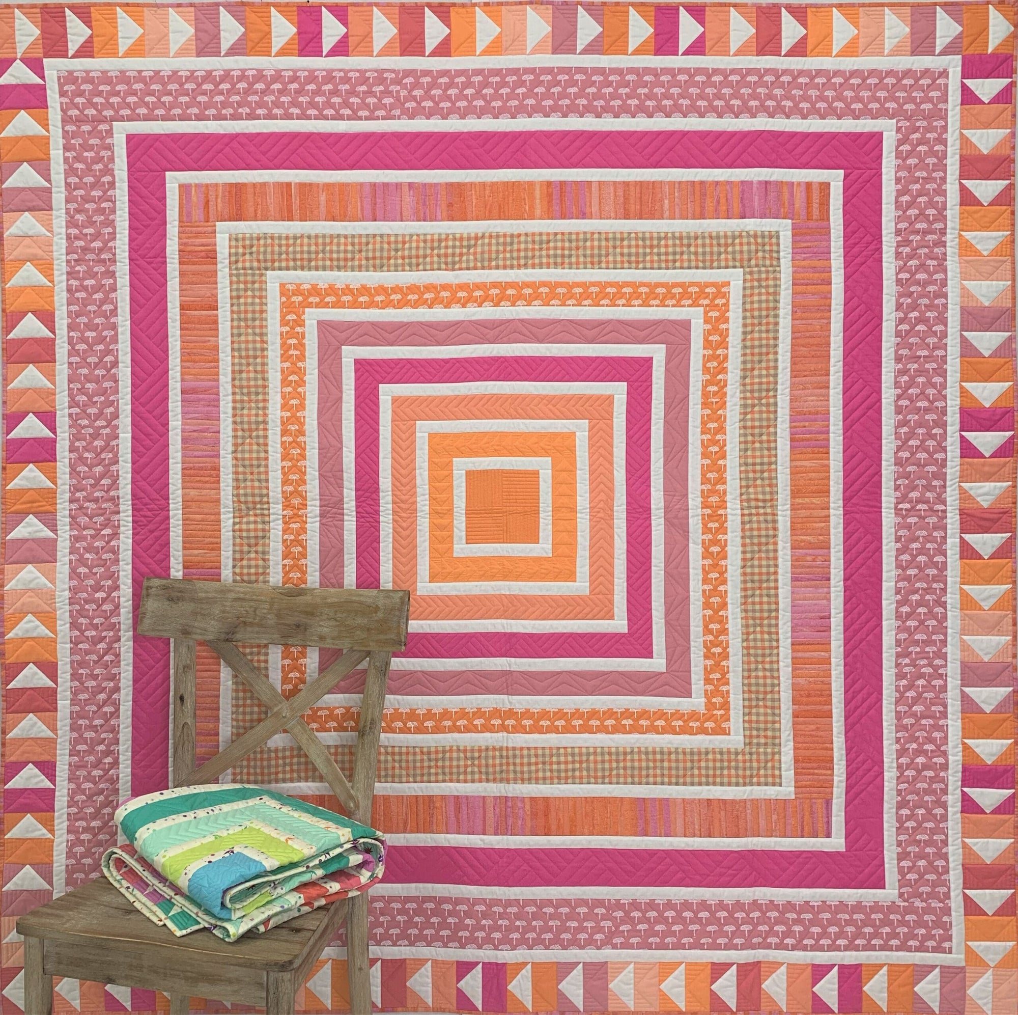 A quilt with an orange and pink design on it.