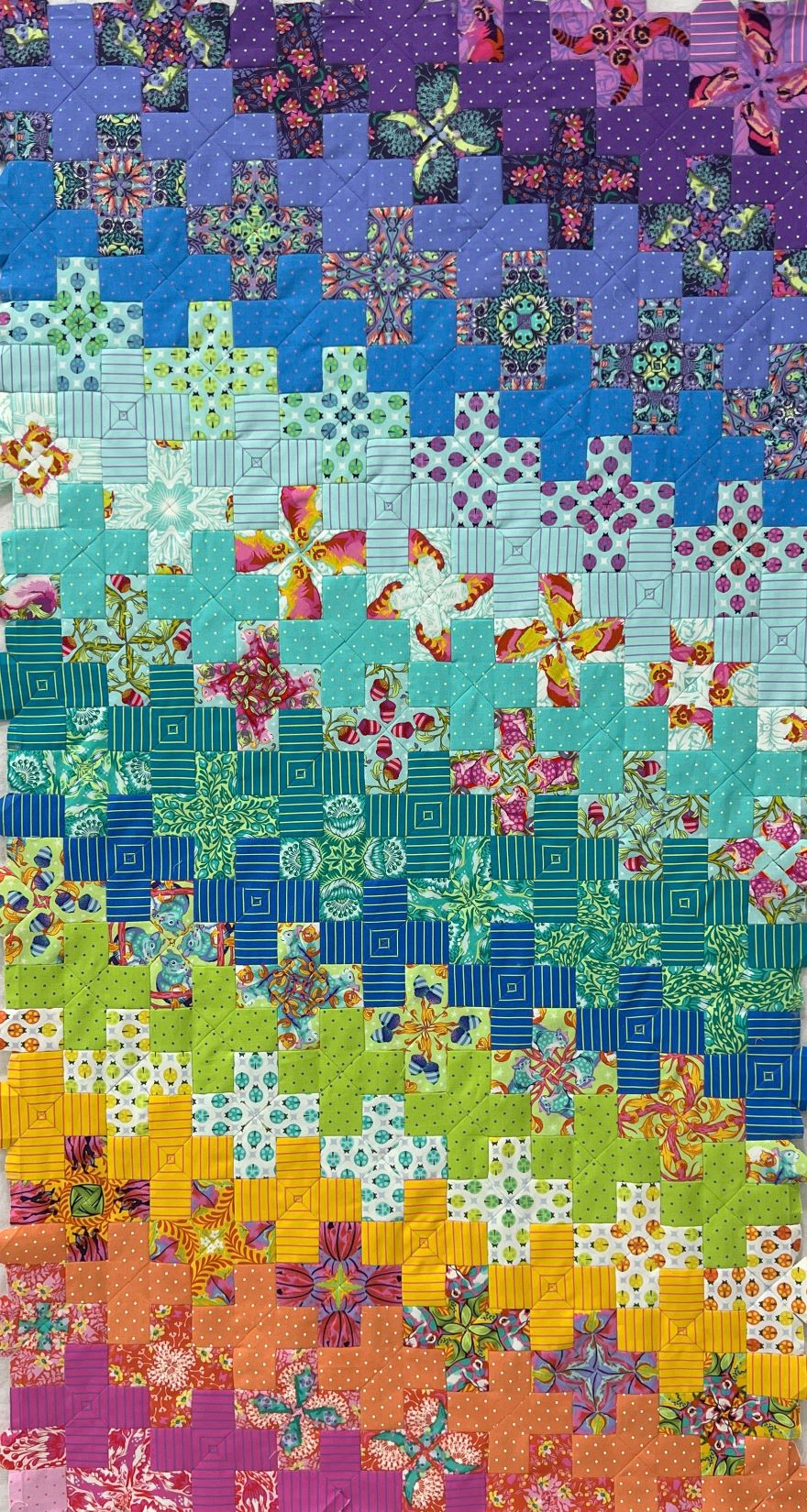 A quilt with crosses on it is colorful.