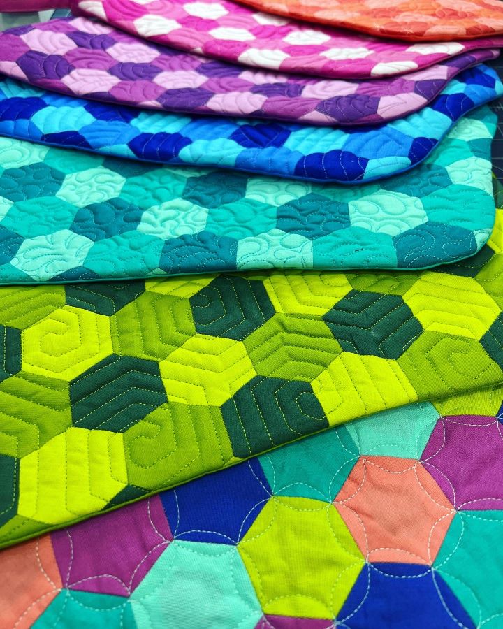 A close up of several different colored quilts
