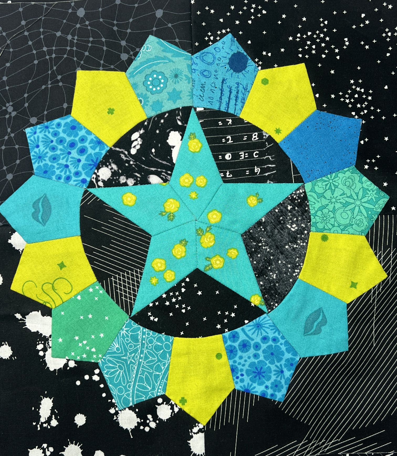 A colorful star design surrounded by geometric shapes on a dark speckled background.