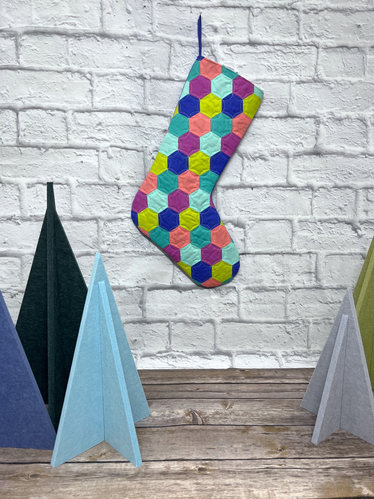 A colorful stocking hanging on the wall next to some other items.