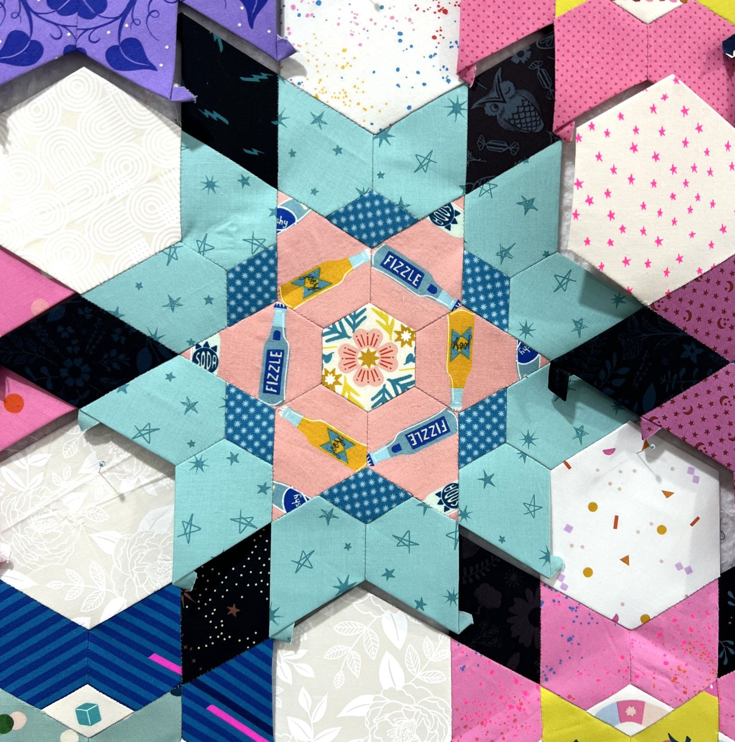 Colorful geometric quilt pattern with stars and hexagons.