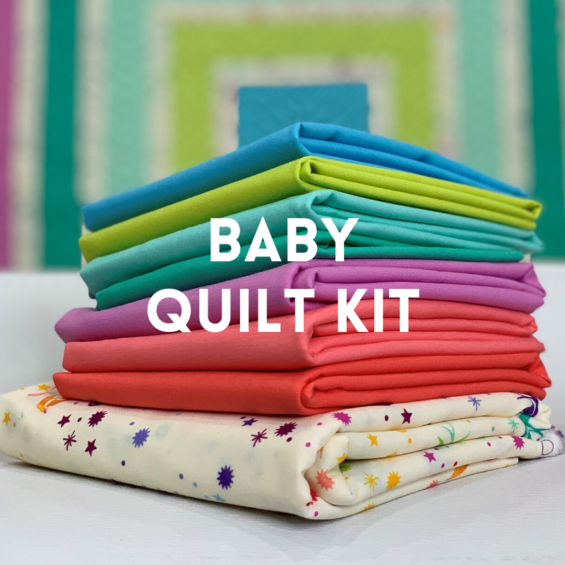 A stack of baby quilt kits in different colors.