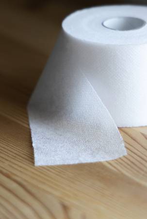 Close-up of white toilet paper on a wooden surface.