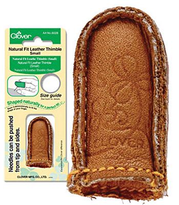 A brown leather thimble with a stitch on it.