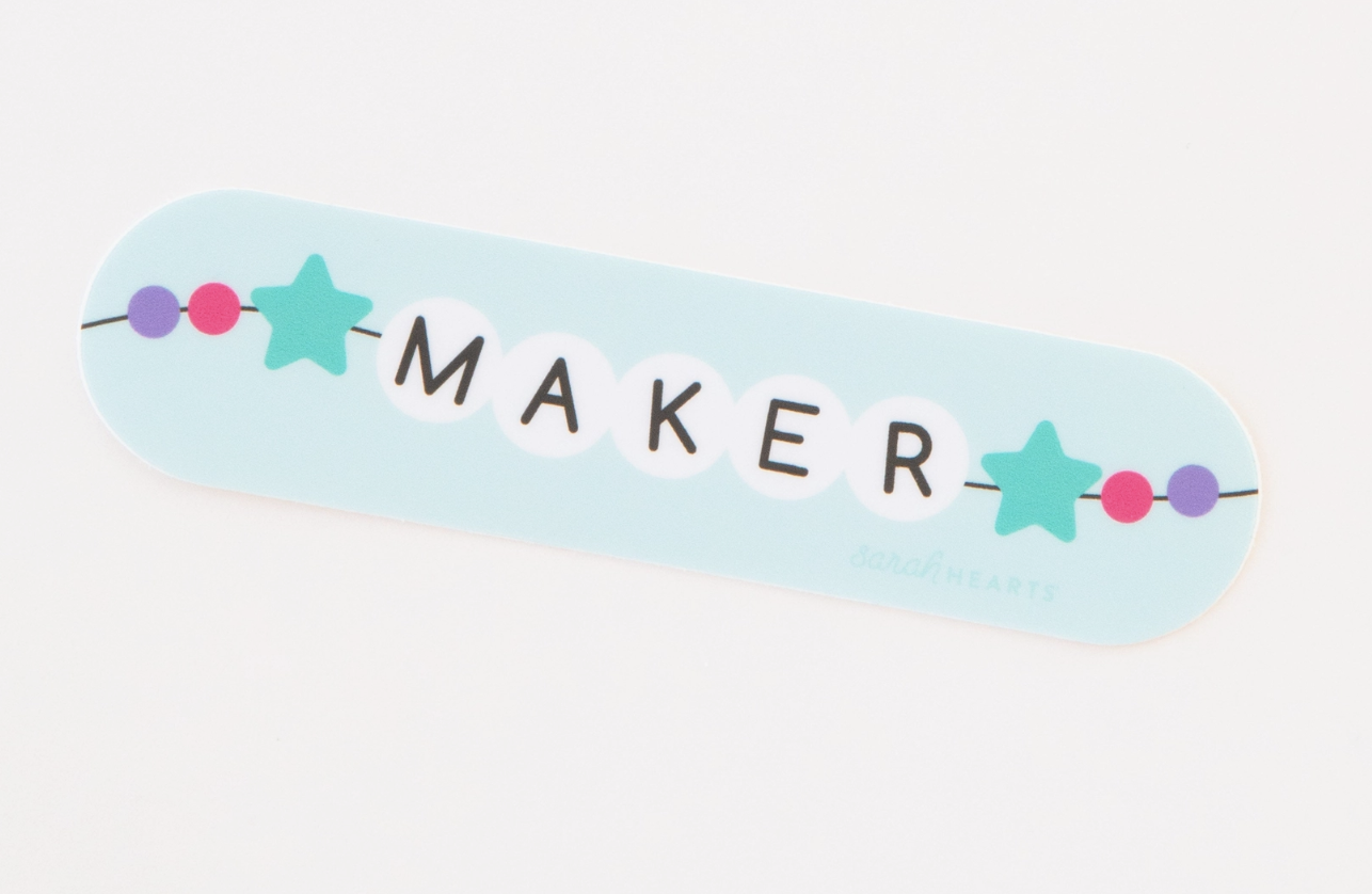 White beads spelling 'MAKER' with star-shaped beads on a blue strip.