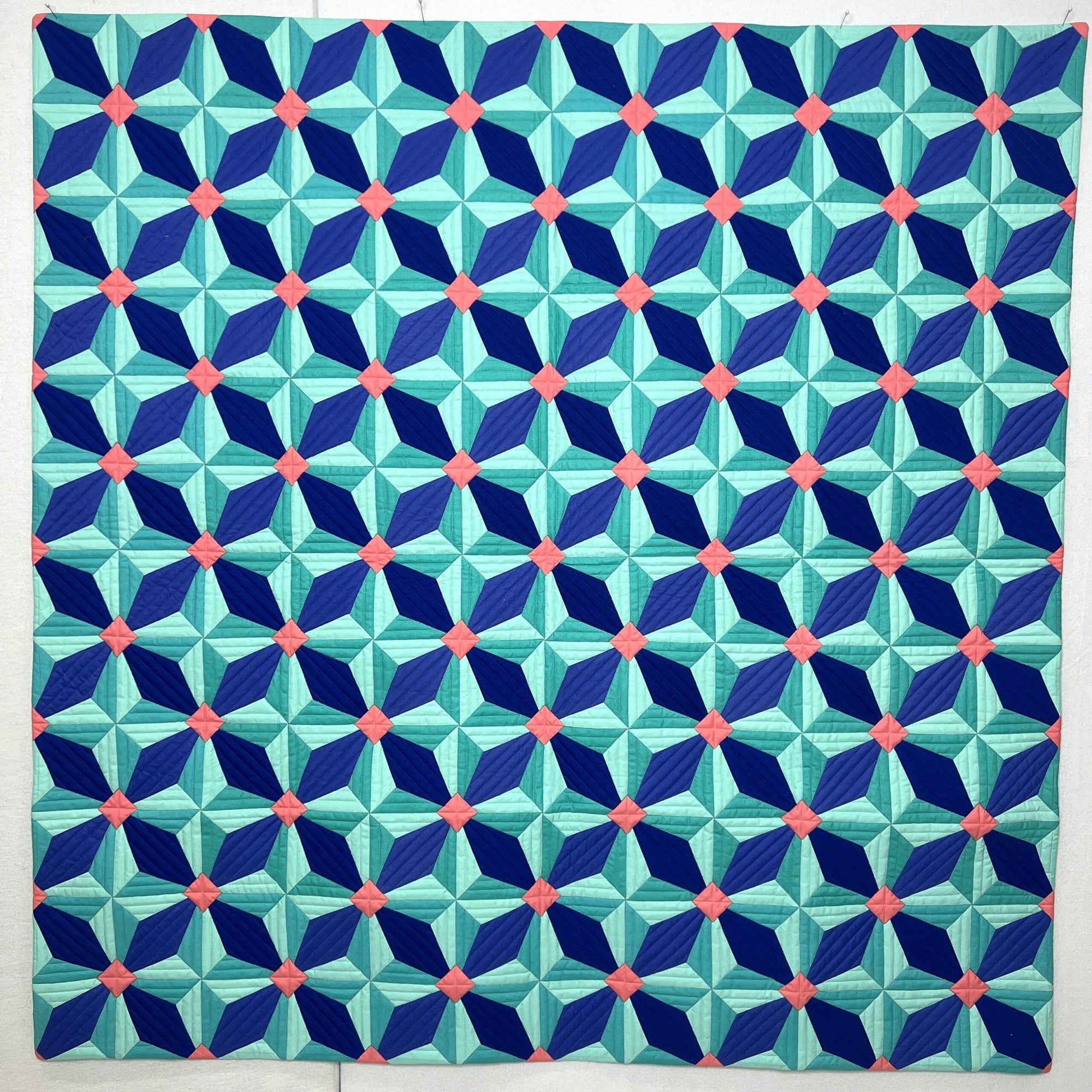A geometric quilt with star-shaped blue, green, and white patterns.