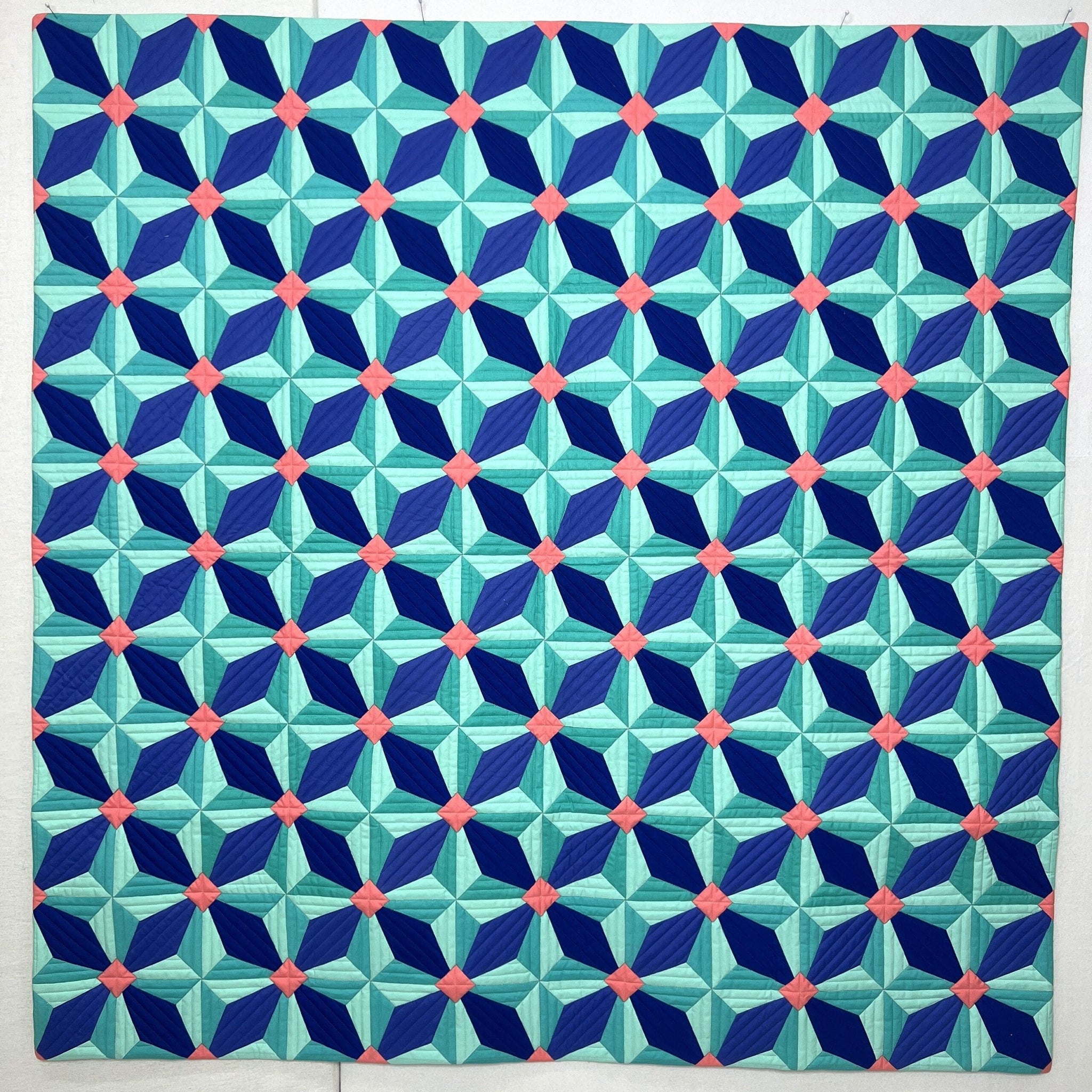 A geometric quilt with star-shaped blue, green, and white patterns.