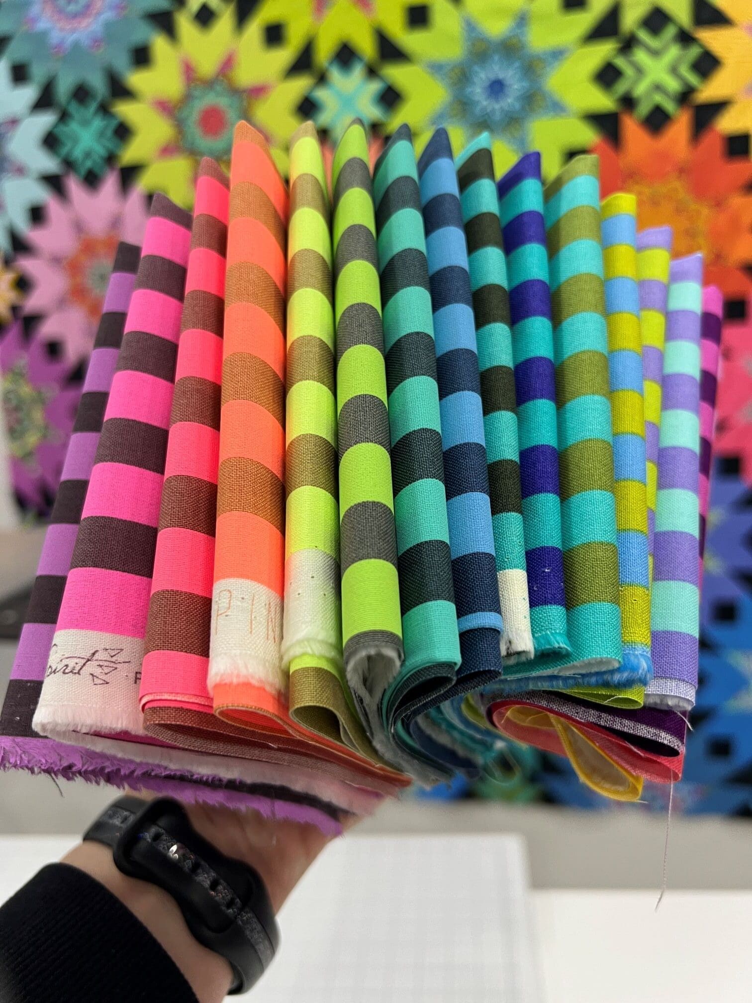 A hand holding up a stack of colorful paper straws.