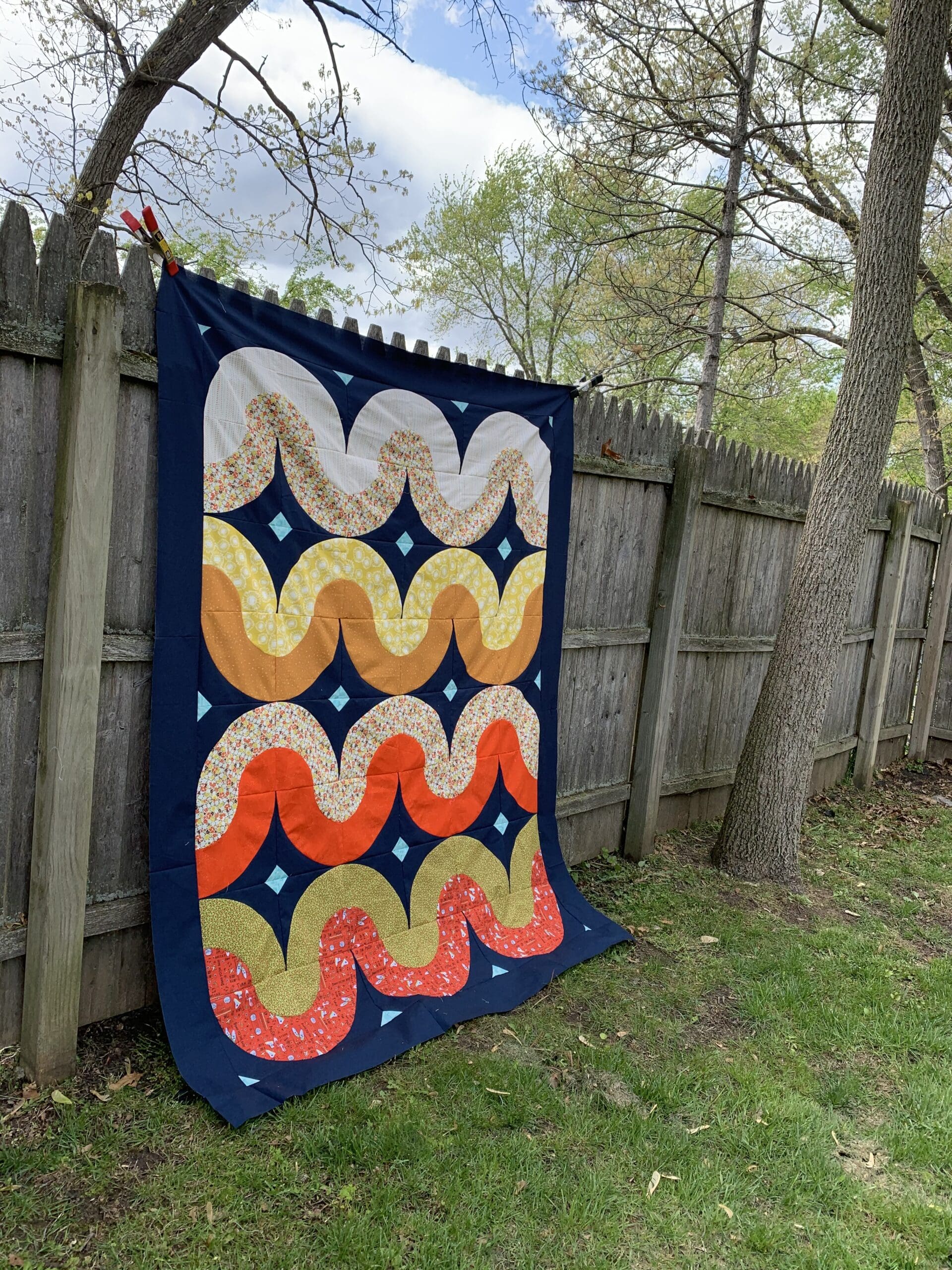 A quilt hanging on the side of a fence.