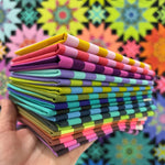 A stack of folded paper in front of a colorful background.