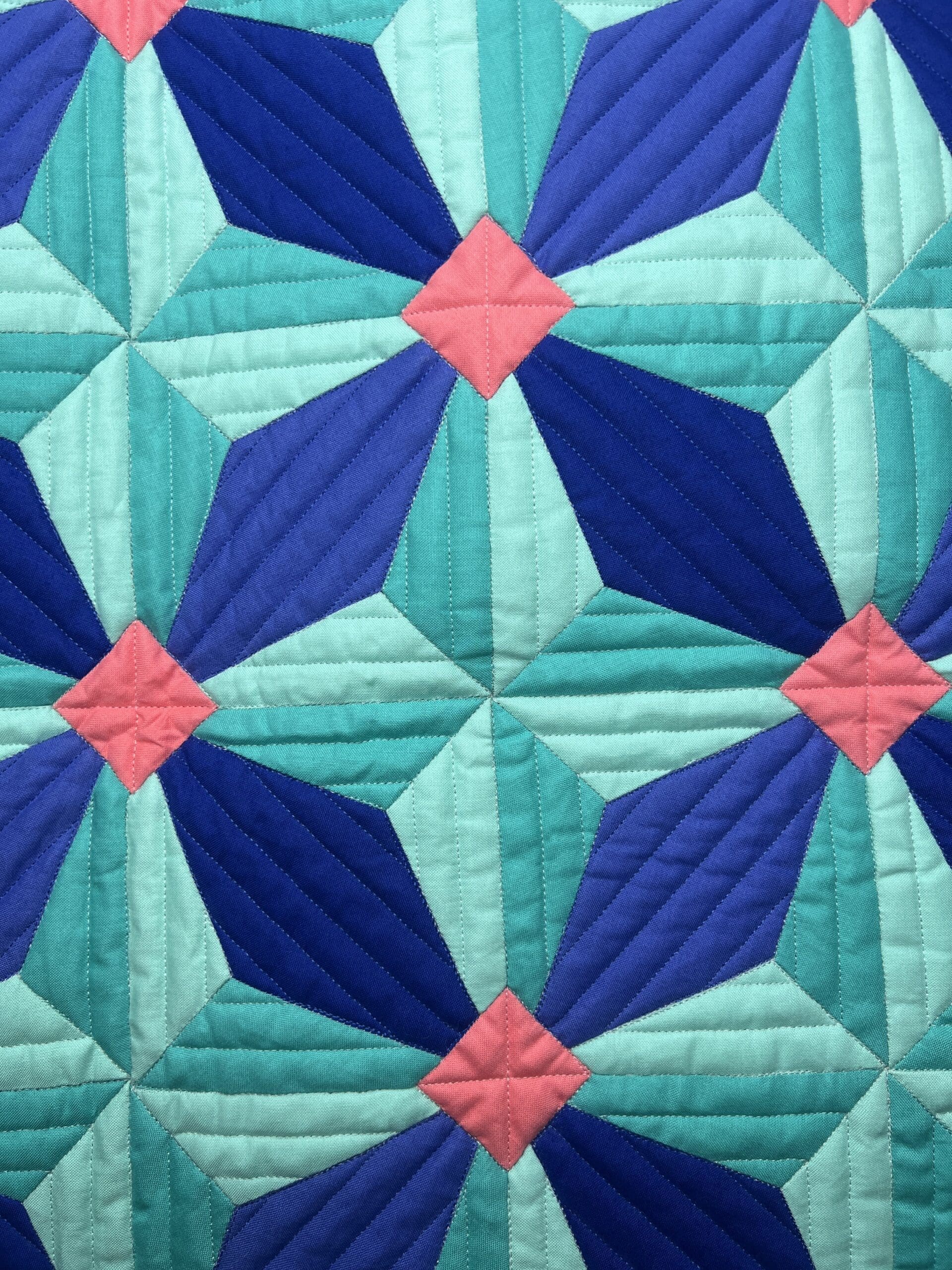 Close-up of a colorful quilt with geometric patterns in blue and pink.