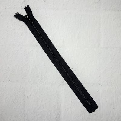 A black zipper is laying on the floor.
