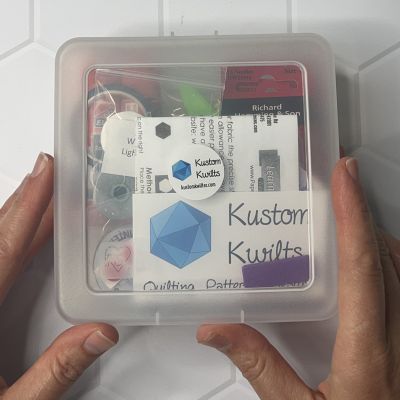 A person holding a transparent box filled with knitting supplies.
