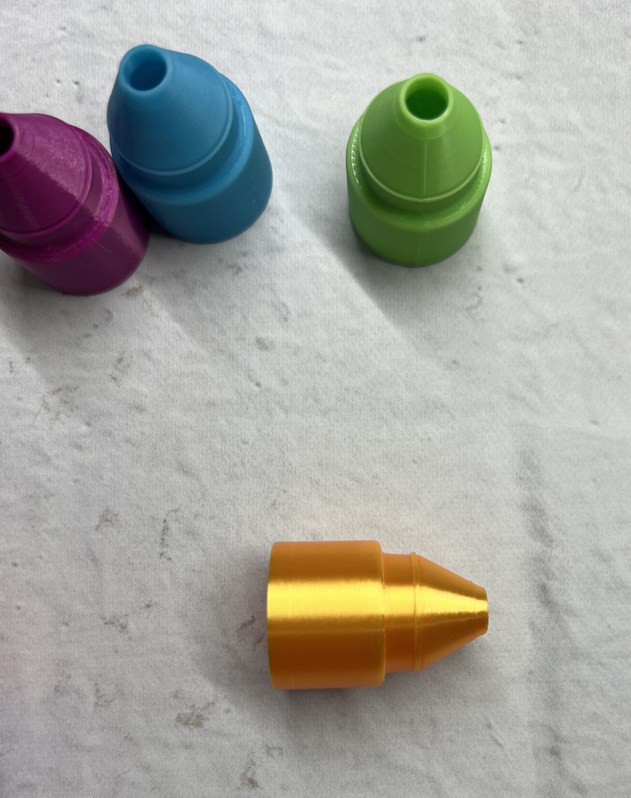 Four colorful plastic cones arranged on a white surface.
