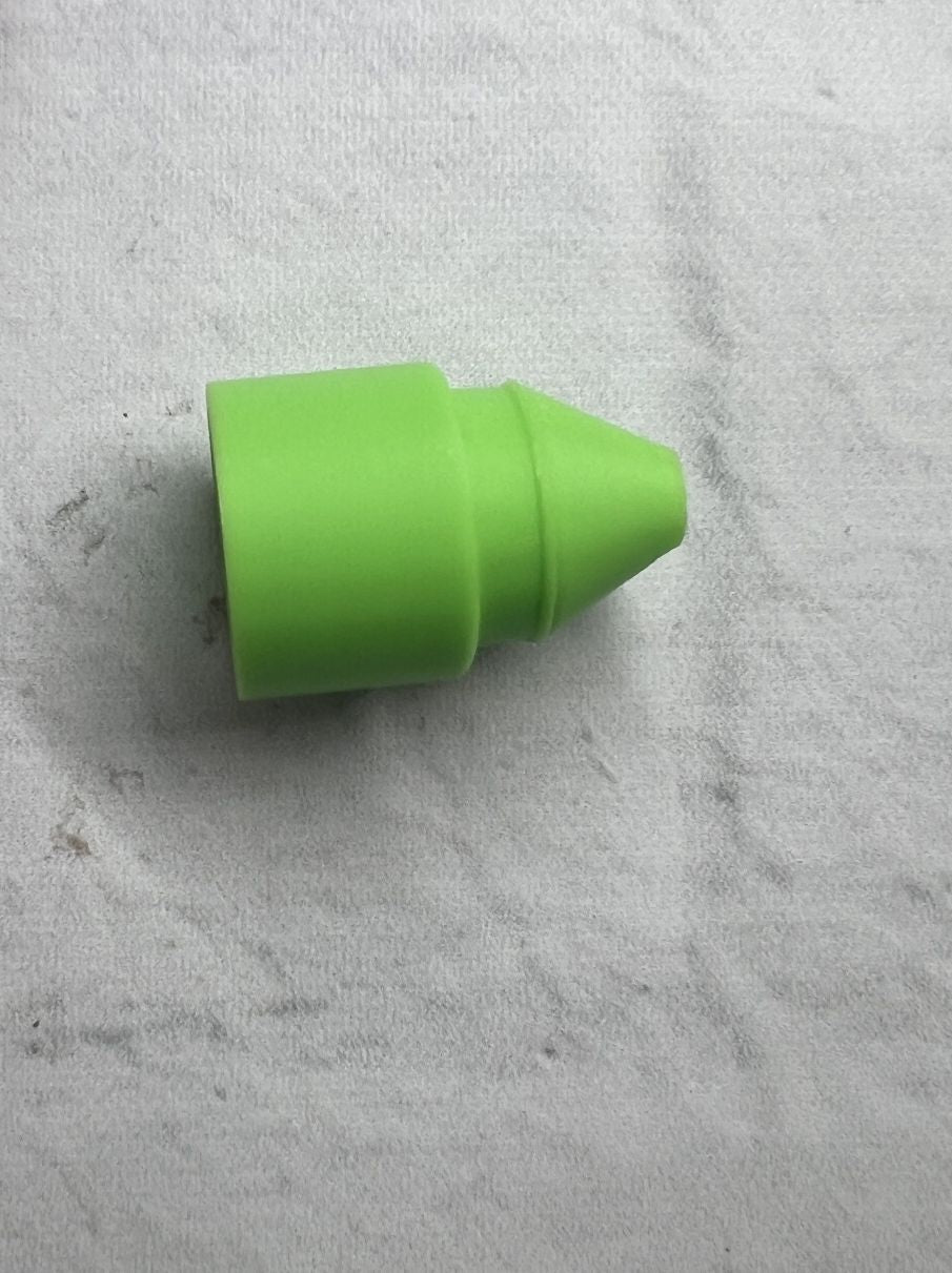 Small green plastic cone-shaped object on a textured surface.