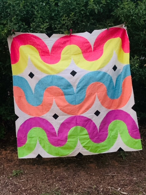 A colorful quilt hanging on the side of a tree.
