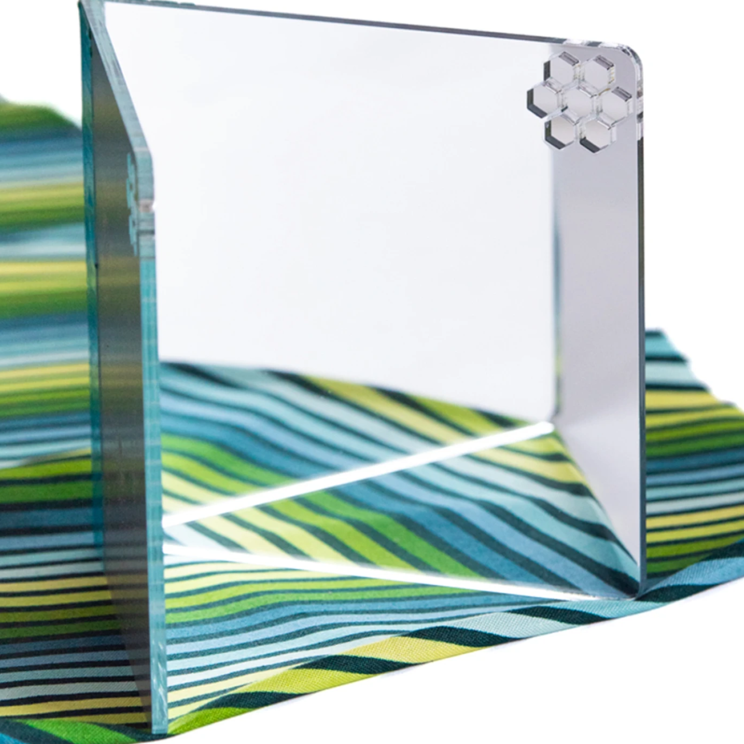 A clear acrylic photo frame with a flower decoration on a striped fabric surface.