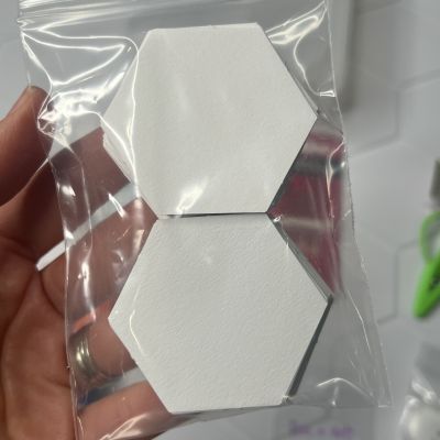 Two white hexagonal tiles in clear plastic packaging.
